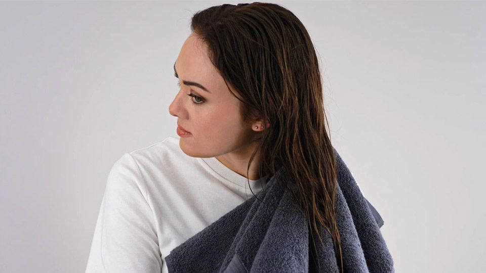 Person trocknet Haar mit Handtuch 