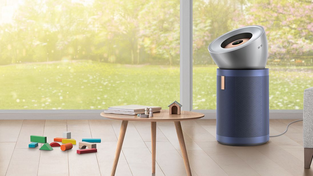 A Dyson purifier placed near a table with toys in a sunny room, highlighting its ability to reduce allergens for cleaner air.