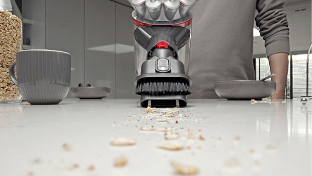 The Combination tool is used with a Dyson vacuum to clean crumbs from a kitchen worktop.