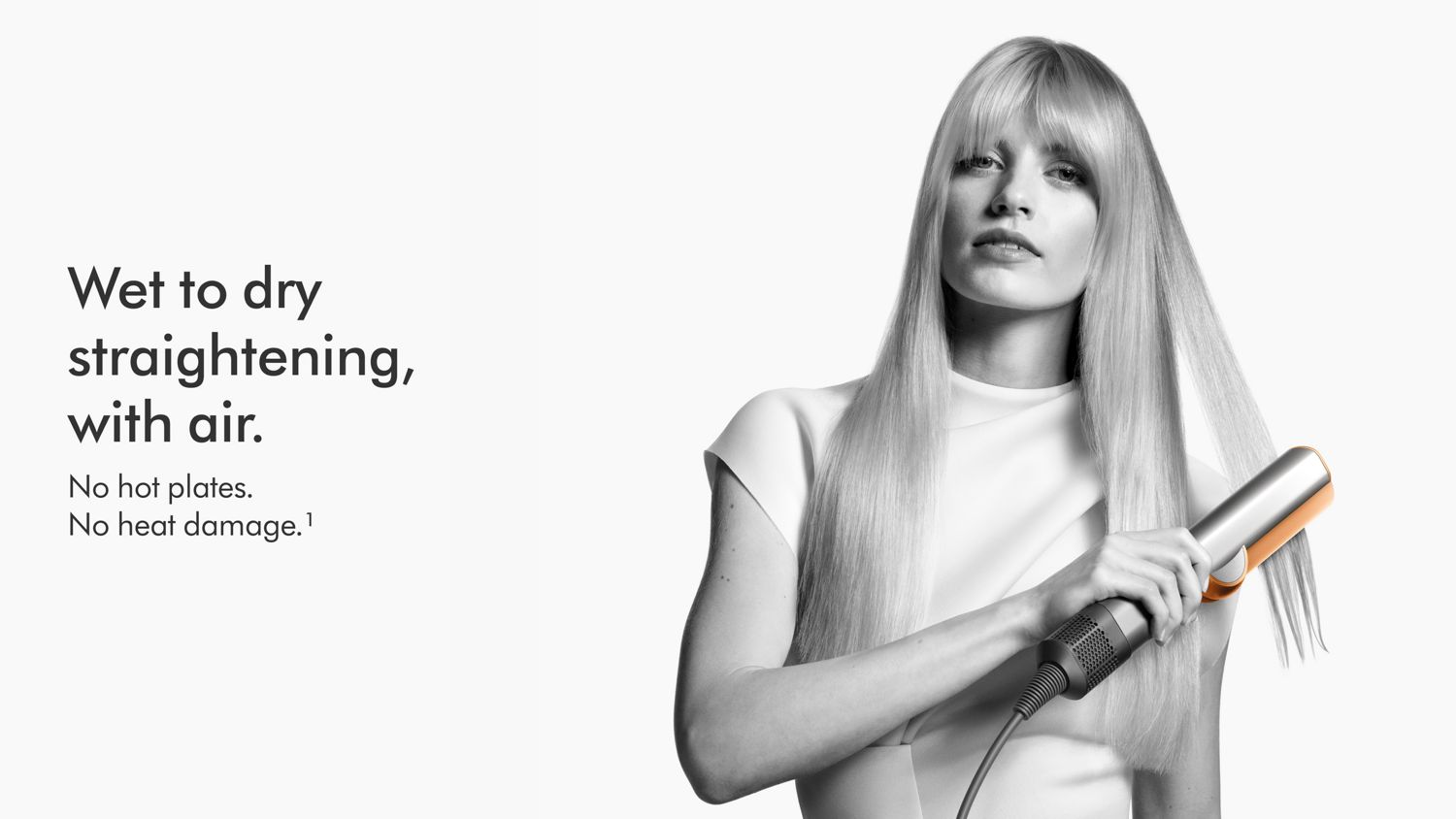 Una modella con capelli lunghi e lucidi che utilizza la piastra Dyson Airstrait.