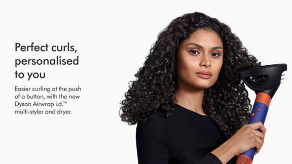 Model using the Dyson Airwrap i.d. multi-styler and dryer with Wave + Curl diffuser to enhance natural curls.