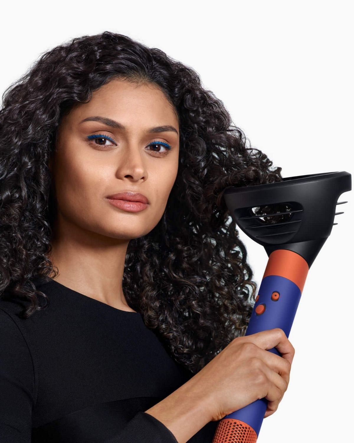 Model using the Dyson Airwrap i.d. multi-styler and dryer with Wave + Curl diffuser to enhance natural curls.