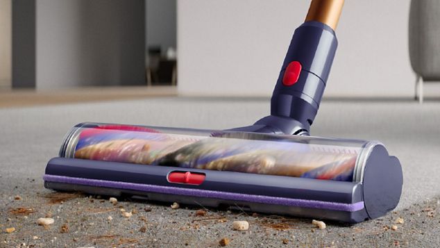 A close-up of a Dyson cordless vacuum cleaner head removing debris from carpet.