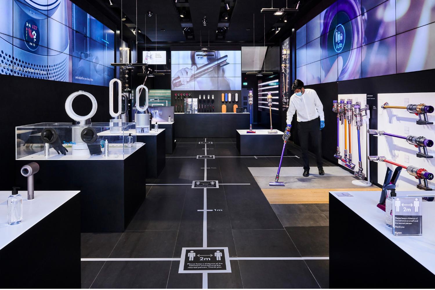 Dyson expert in mask using Dyson cordless vacuum to clean Dyson Demo store.