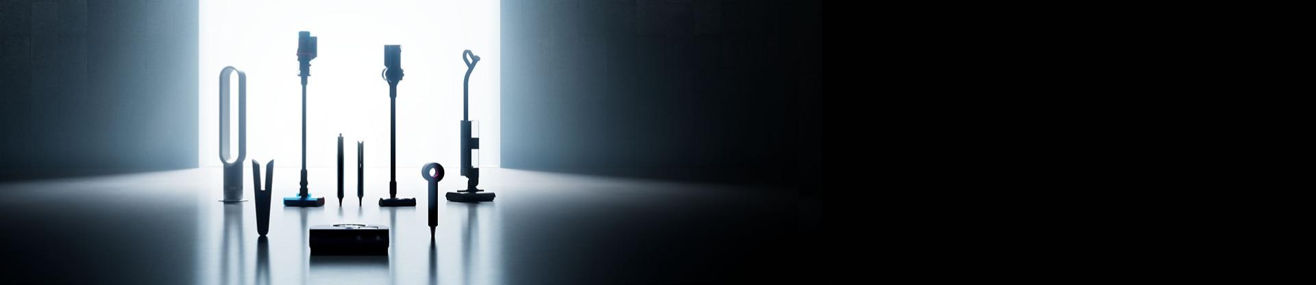 A lineup of sleek Dyson appliances, including vacuums, hair tools, and an air purifier, arranged in a dark room.