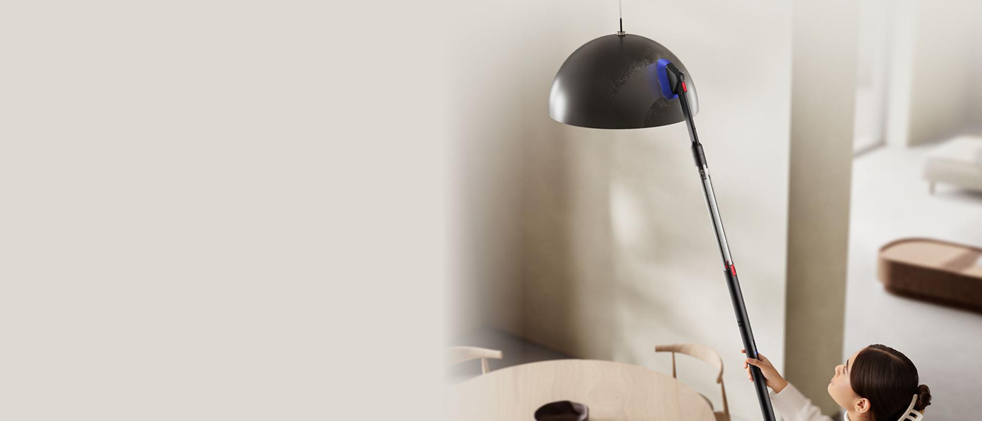 Bir abajuru temizlemek için ikili aralık temizleme başlığıyla birlikte kullanılan Dyson PencilVac kablosuz süpürge.