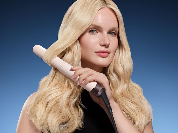 Model curls her hair with the Dyson Corrale CoolShine hair straightener.