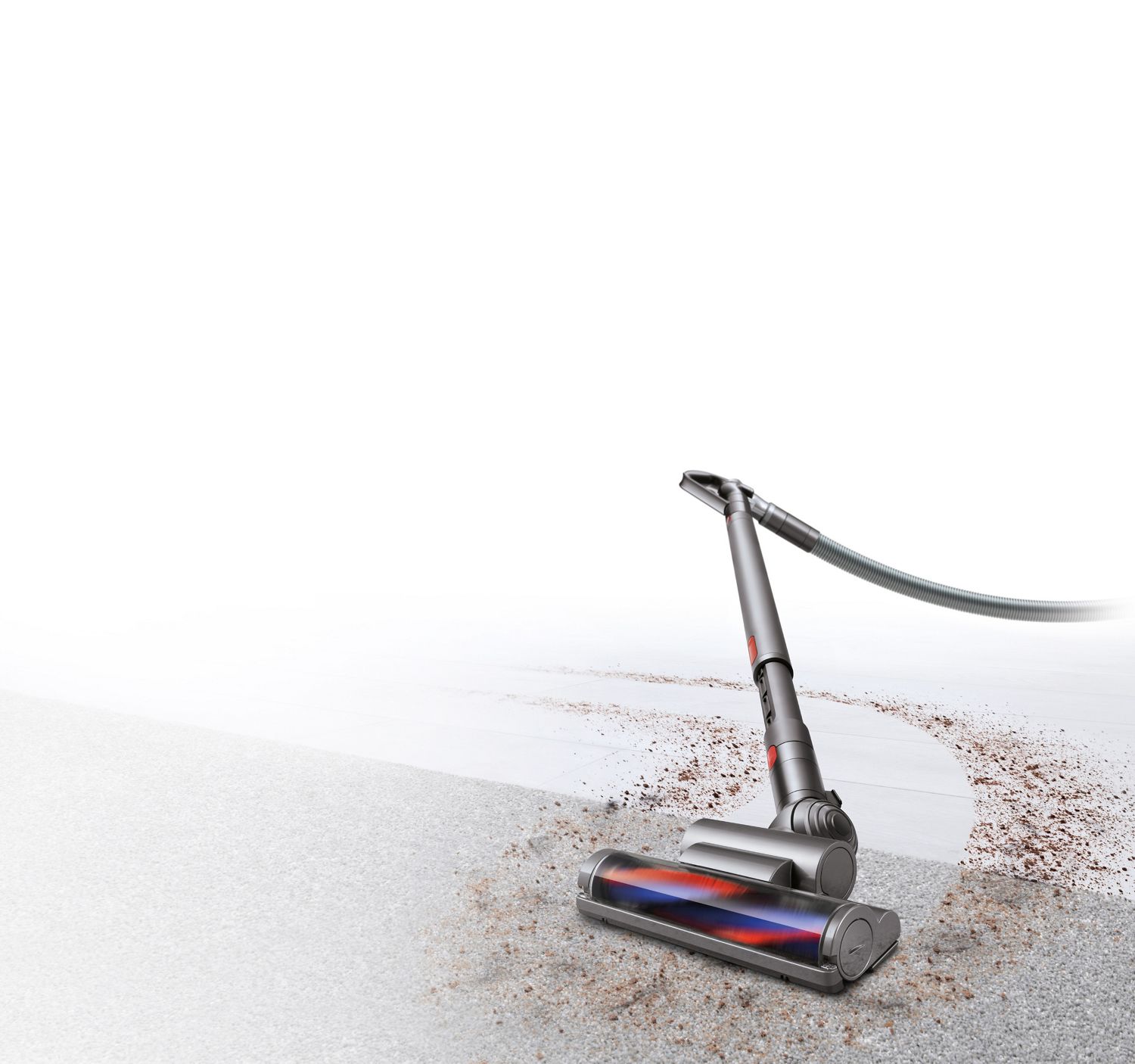 Un aspirateur-traîneau Dyson Cinetic Big Ball ramassant des débris sur un tapis et un plancher dur