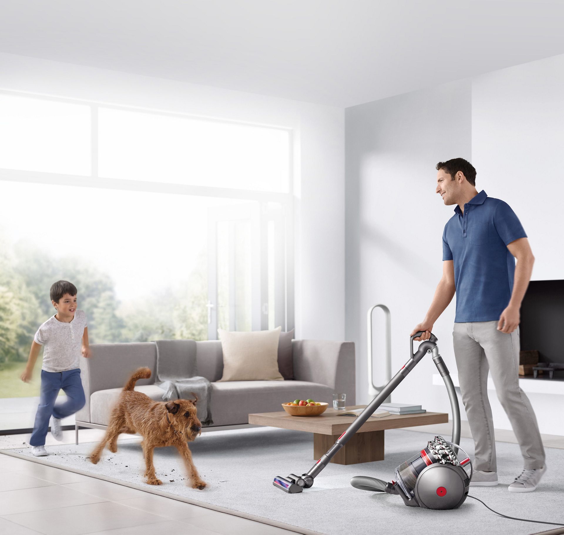 Man vacuuming in room with dog and child