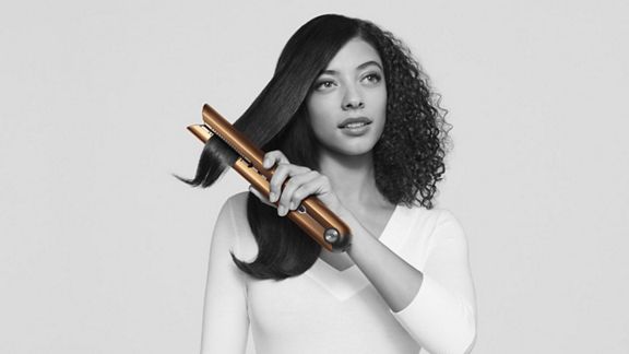 Femme utilisant le fer plat Dyson Corrale.