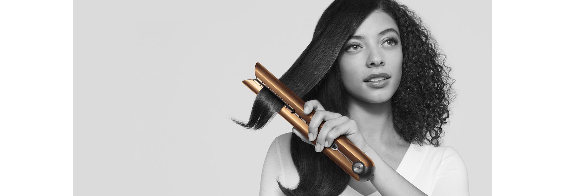 Dyson Corrale straightener being used to straighten curly hair on model