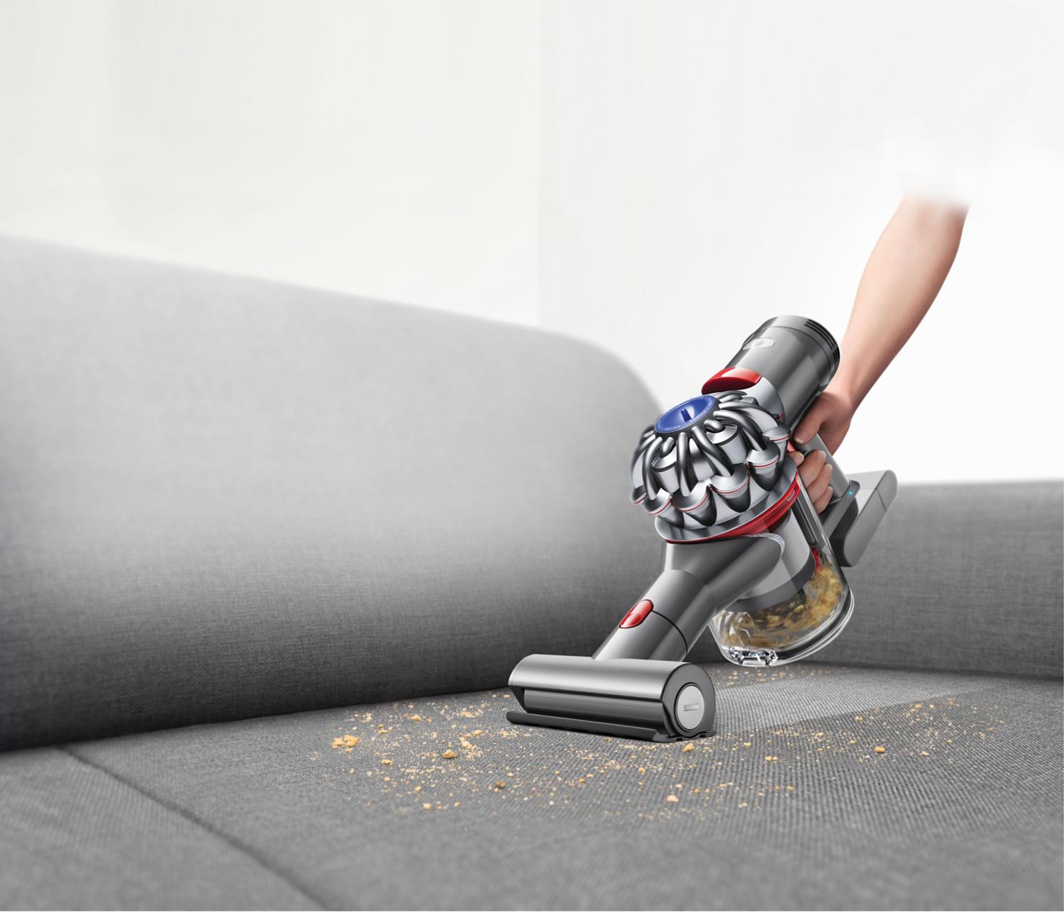 Aspirateur portatif Dyson utilisé sur un sofa