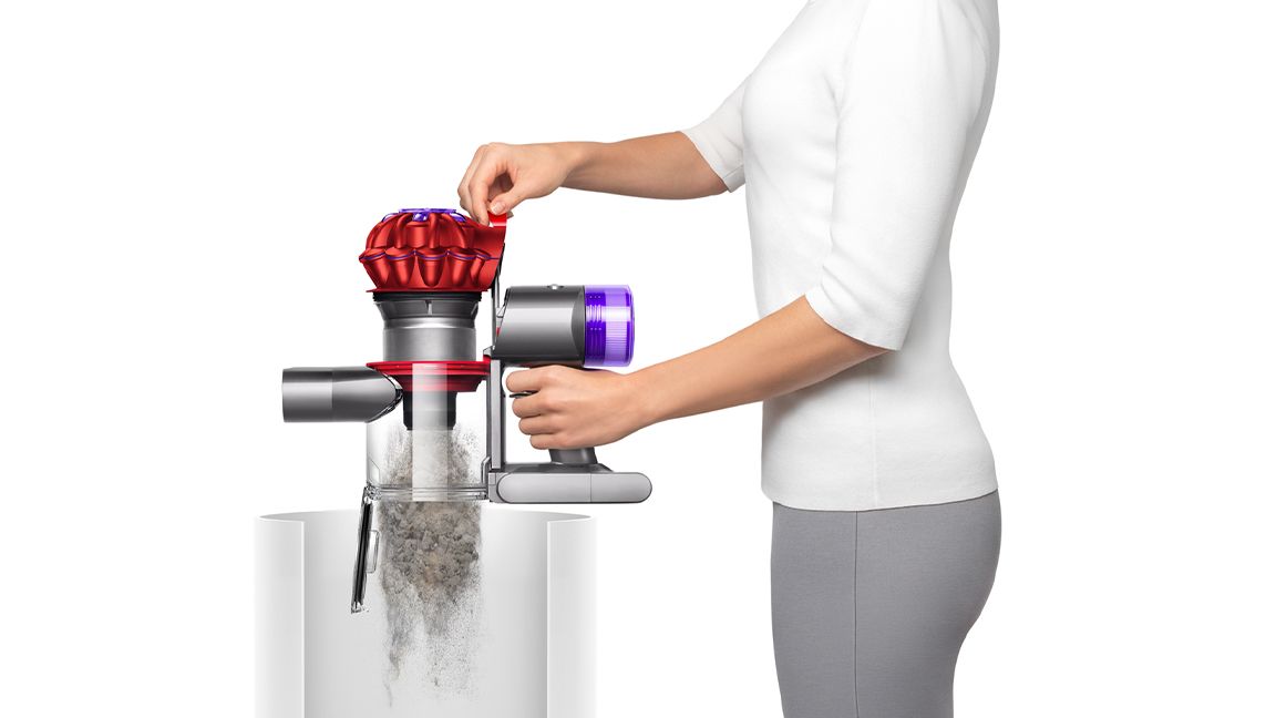 Woman emptying Dyson V8 vacuum into garbage bin
