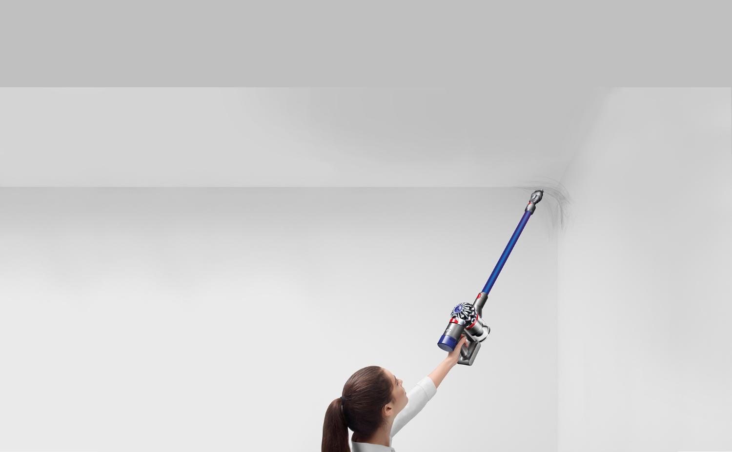Une femme qui utilise l’aspirateur balai V7 dans un coin