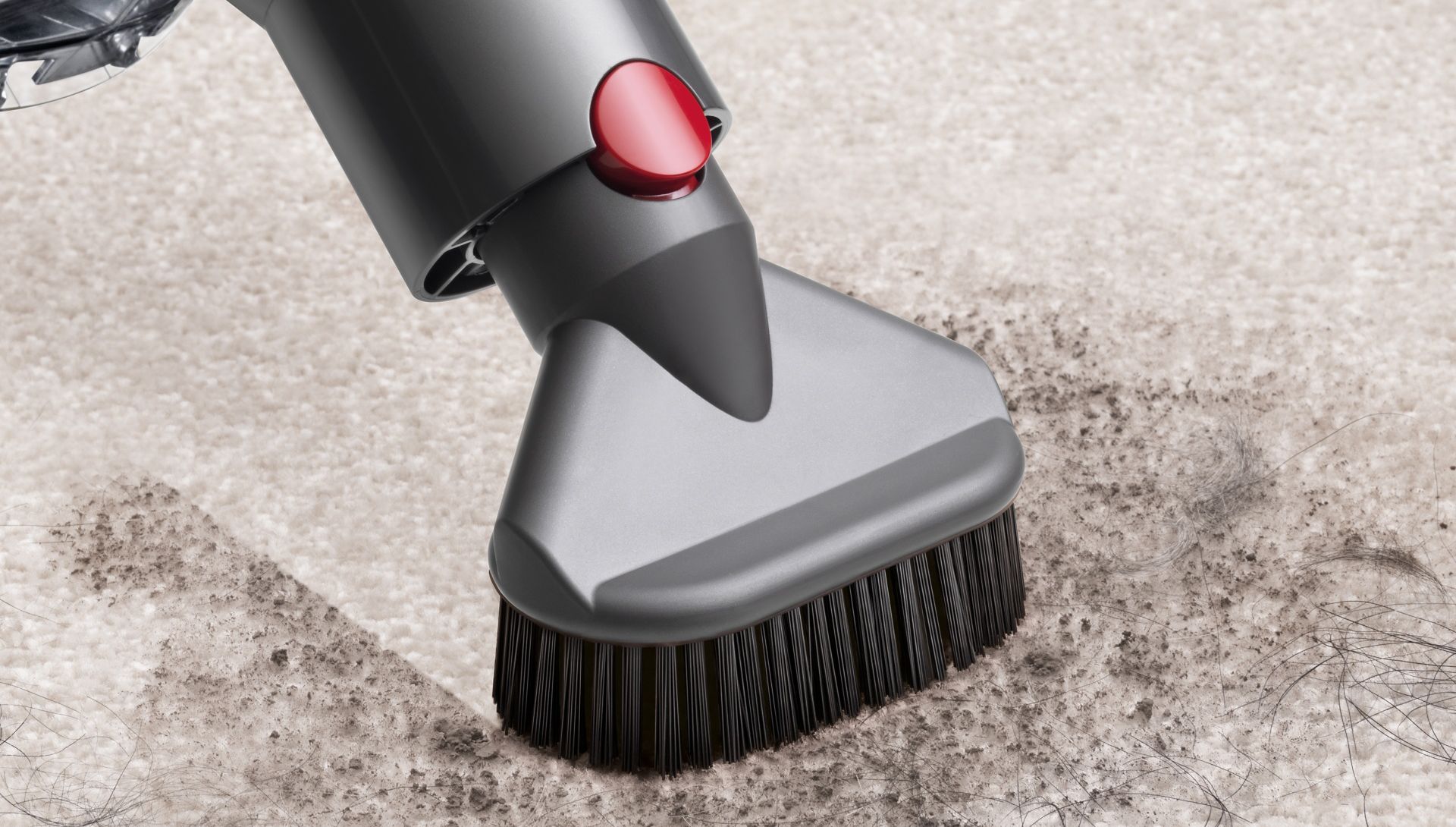Close up of the Stubborn dirt brush tool being used to vacuum dirt and pet hair on a carpet