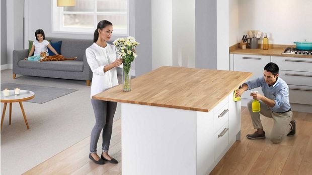 Mężczyzna sprzątający w kuchni, kobieta z bukietem kwiatów w kuchni oraz dziecko głaszczące kota na kanapie w salonie