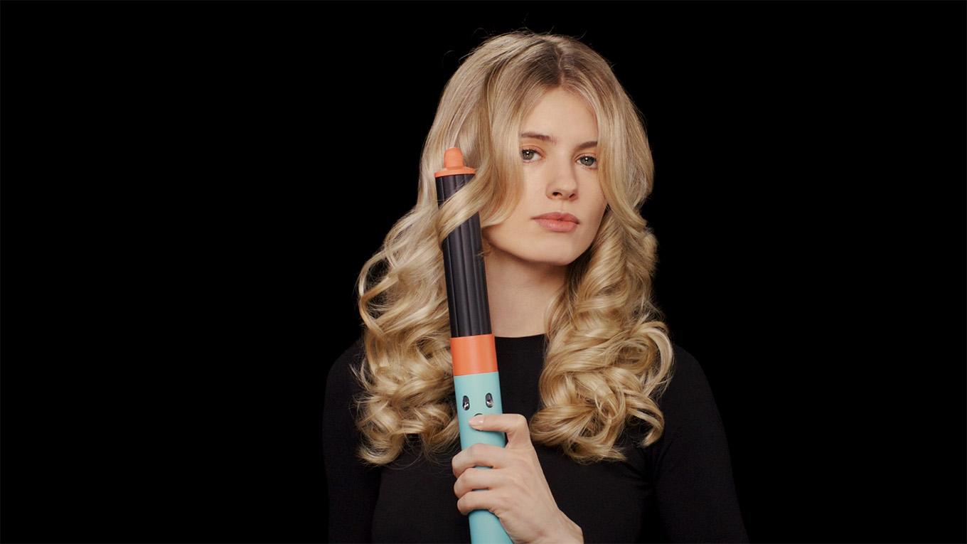 A model styling hair with Dyson Airwrap multi-styler and dryer
