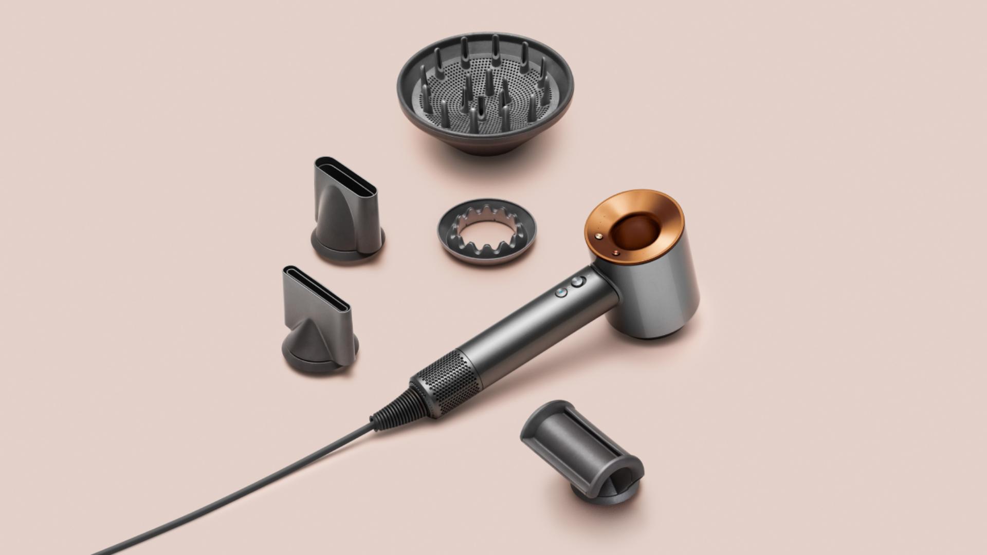 Suszarka do włosow Dyson Supersonic z koncowkami na rozowym tle