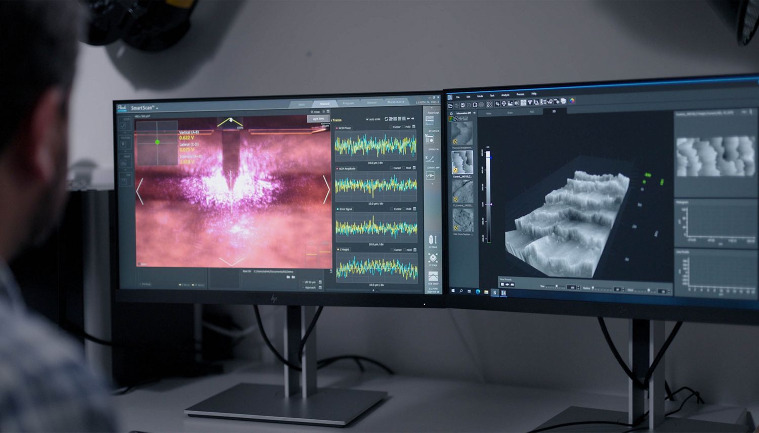 A Dyson engineer examines microscopic views of hair strands while testing machines in a Dyson lab.