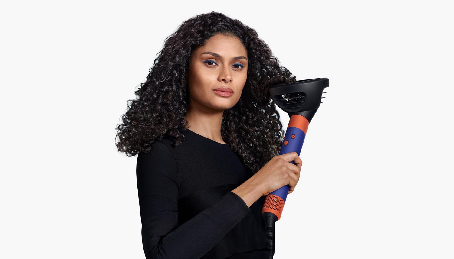 A model uses the Dyson Airwrap ID multi-styler and dryer with the Wave+Curl diffuser in dome mode to enhance her natural curls.