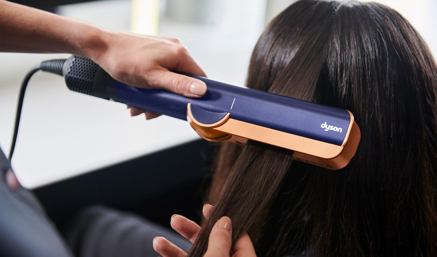 Dyson Aistrait straightener on the back of a model's hair.