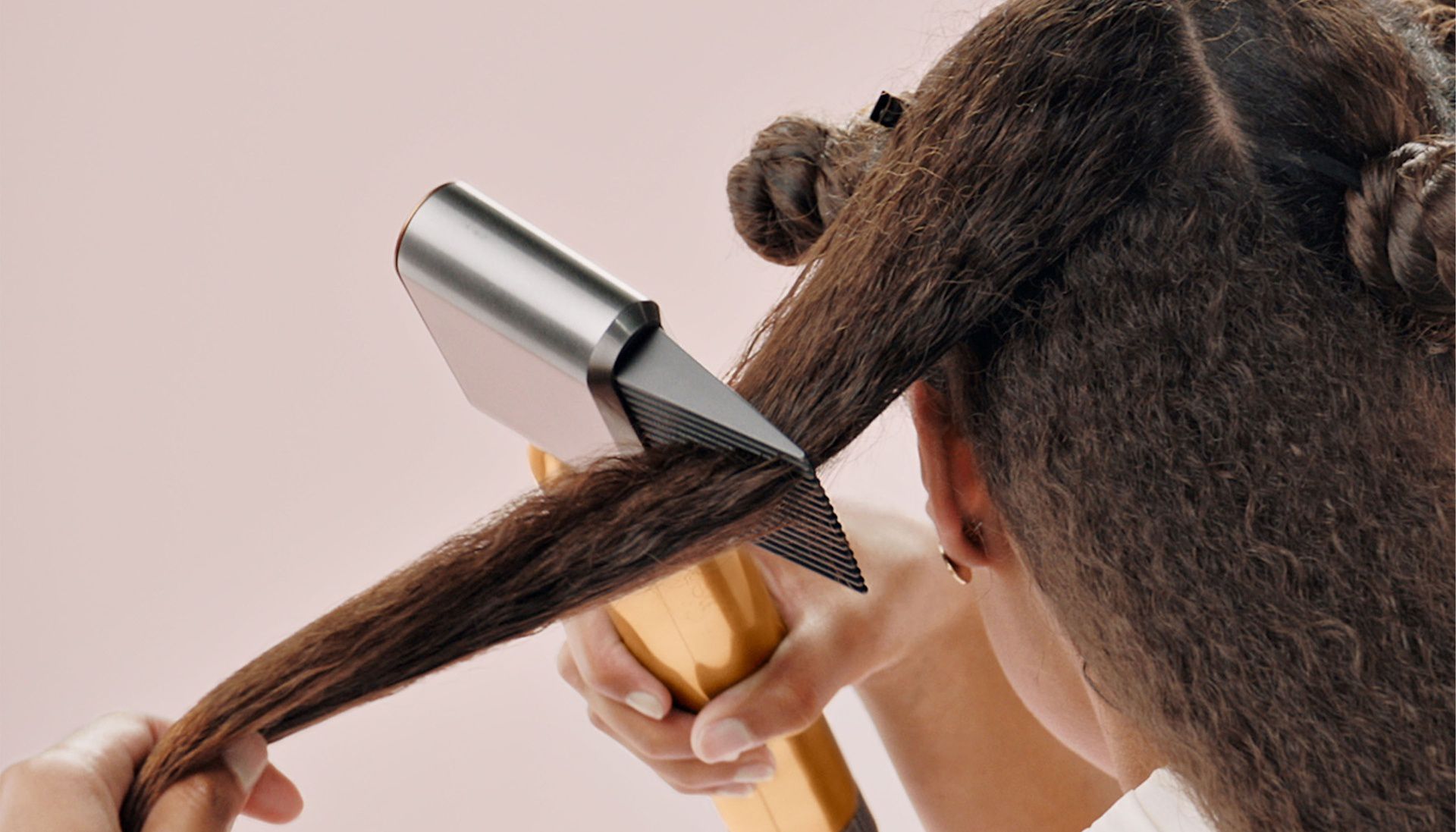 A woman using the Dyson Airwrap™ multi-styler wide-tooth comb do blow dry hair 