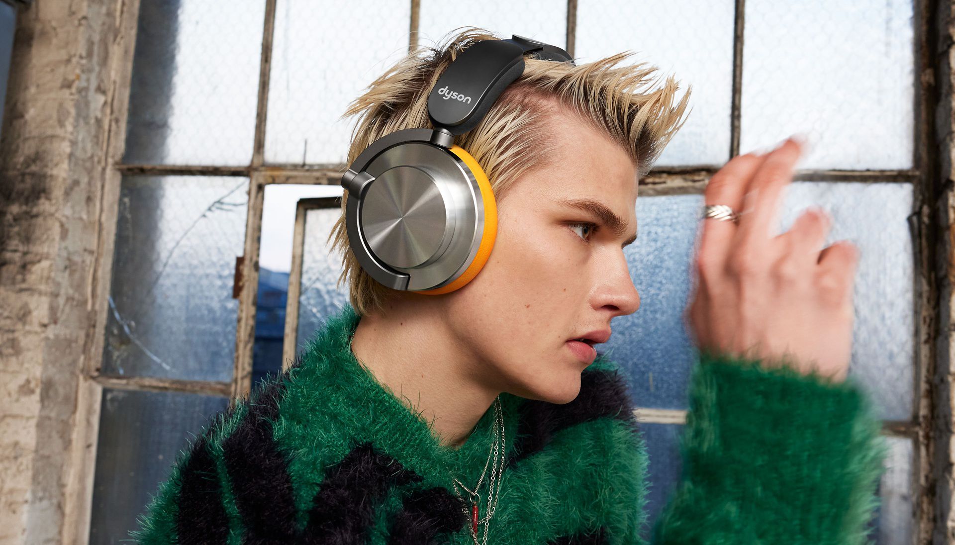 Side profile of Dyson OnTrac headphones in CNC Aluminium and Chrome Yellow worn by male model