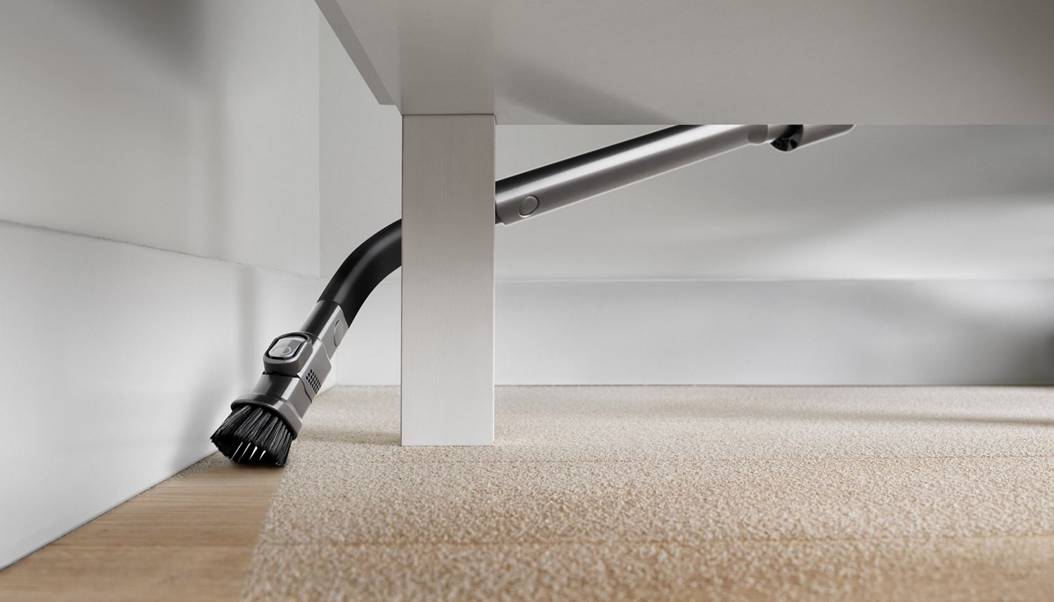 Dyson Flexi crevice tool used to vacuum dust from hard floor under coffee table