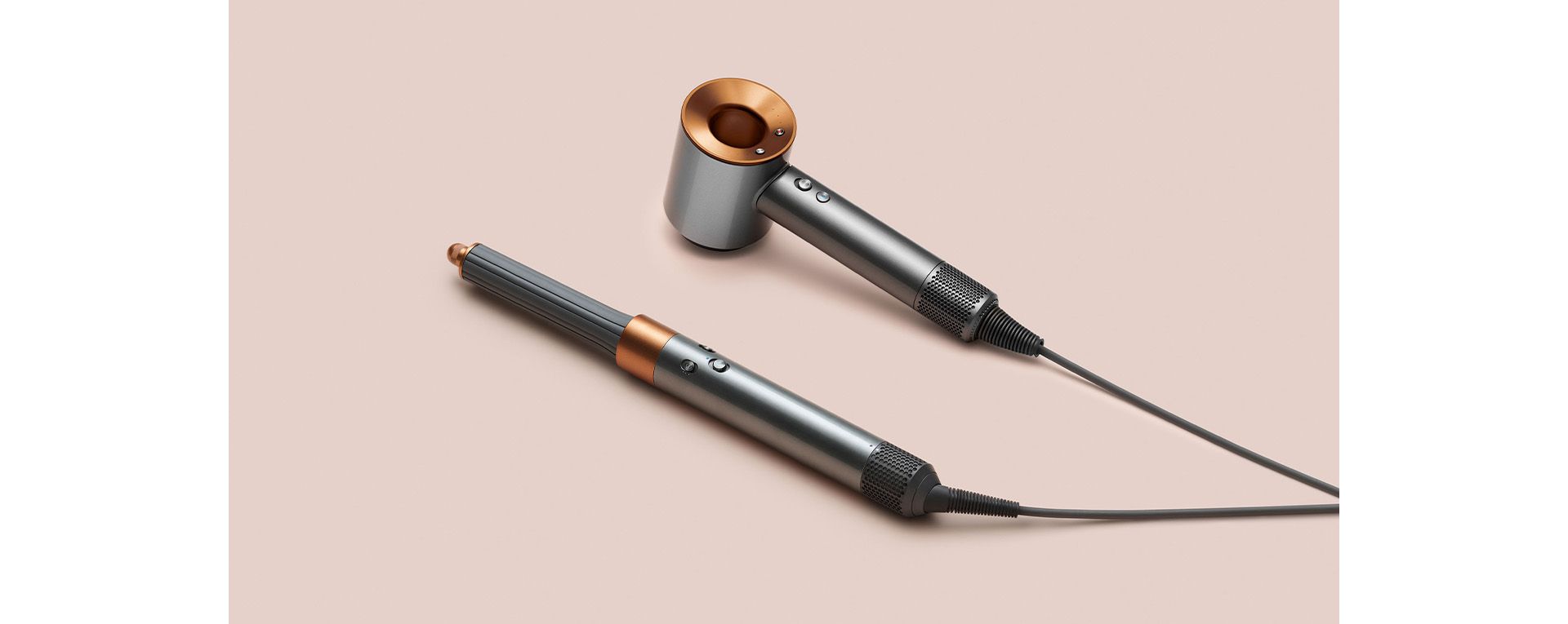 Multistyler Dyson Airwrap i suszarka do włosów Dyson Supersonic na różowym tle