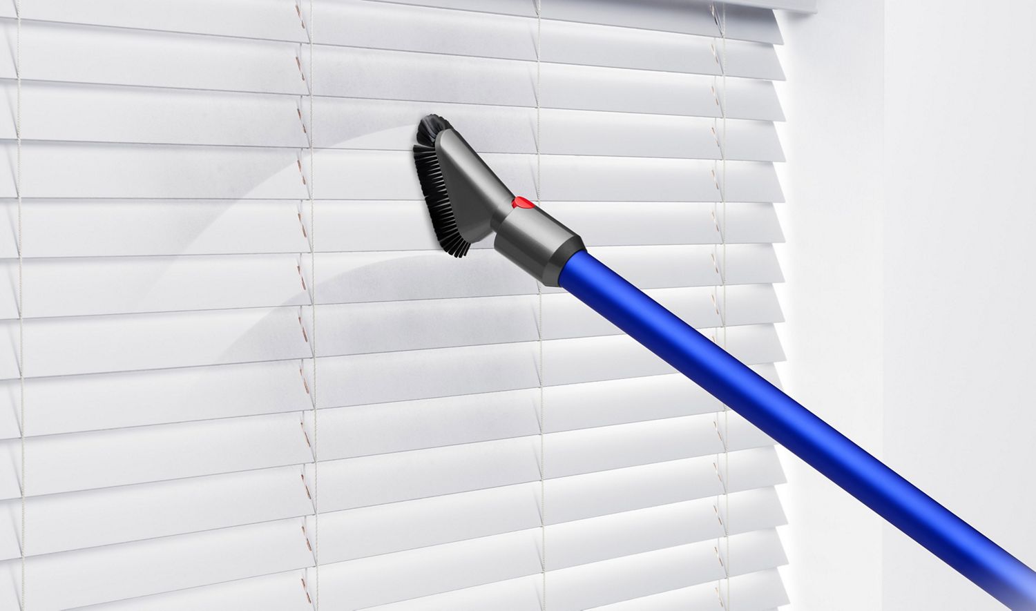 The Mini soft dusting brush being used to vacuum clean white window blinds.