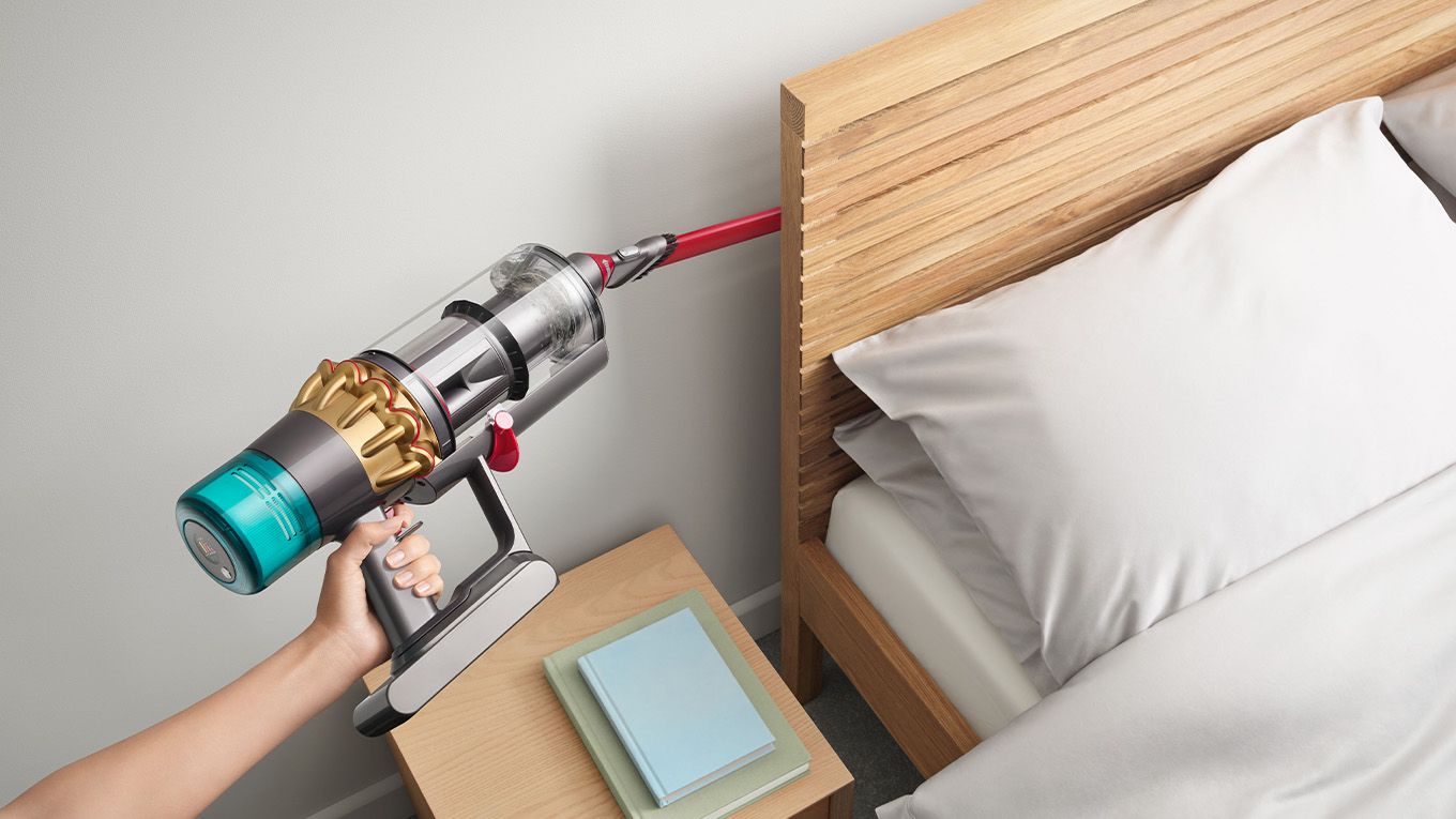 The Dyson Awkward gap tool being used to vacuum behind the bed headboard in the bedroom.