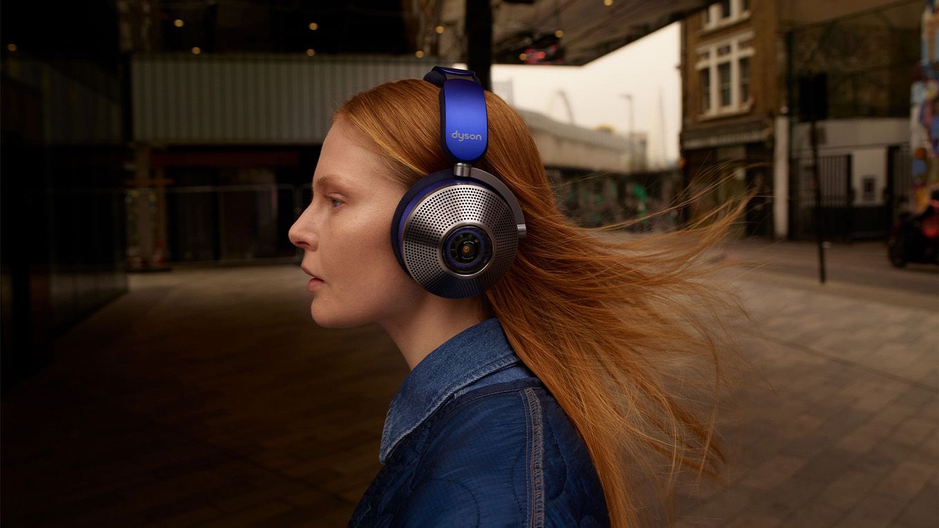 Side view of the Dyson Zone noise-cancelling headphones worn by woman walking down the street