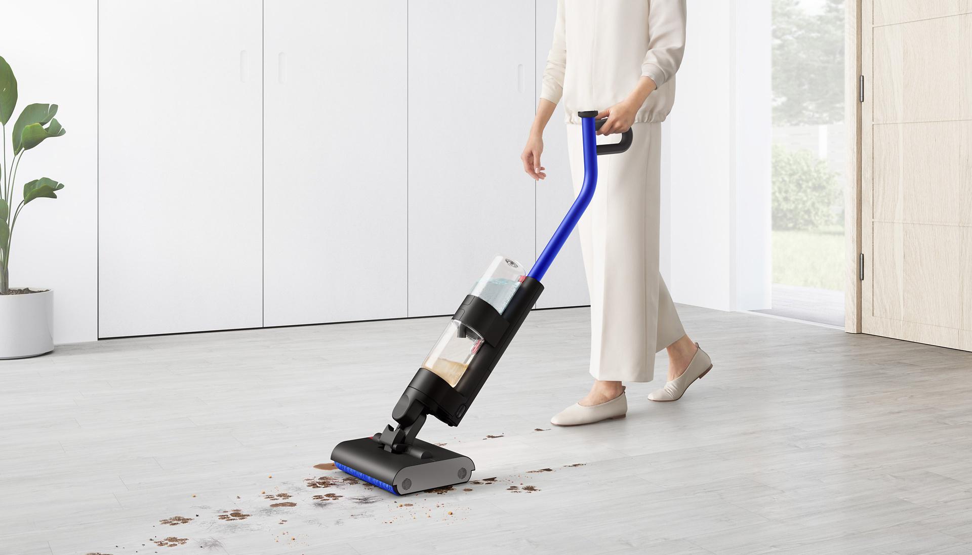 Kobieta używająca wysokoobrotowego mopa elektrycznego Dyson WashG1 do czyszczenia mokrych śladów łap na twardej podłodze