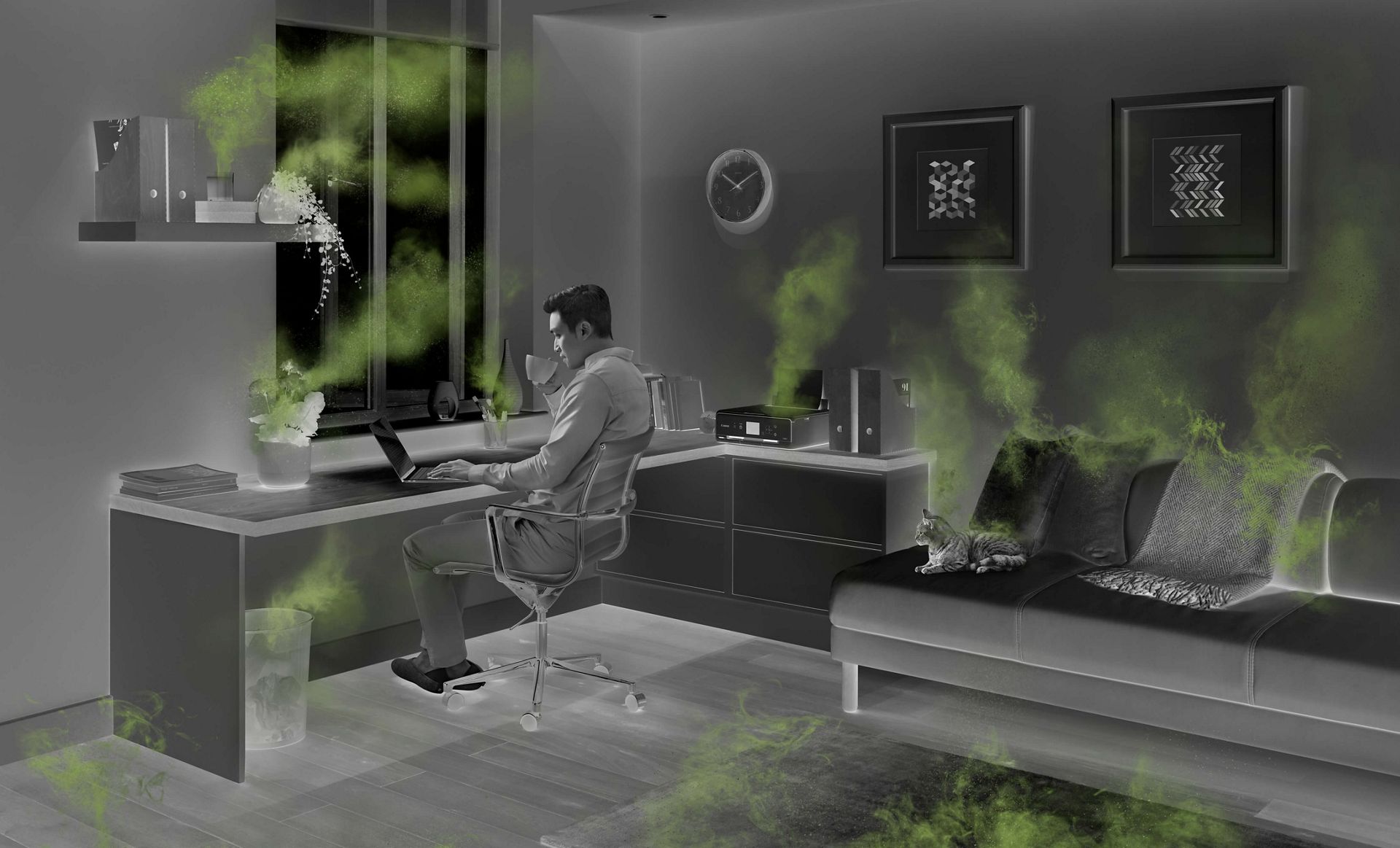  Ein Mann arbeitet im Homeoffice am Schreibtisch mit Gegenständen im Zimmer, von denen Luftverschmutzung ausgeht. 