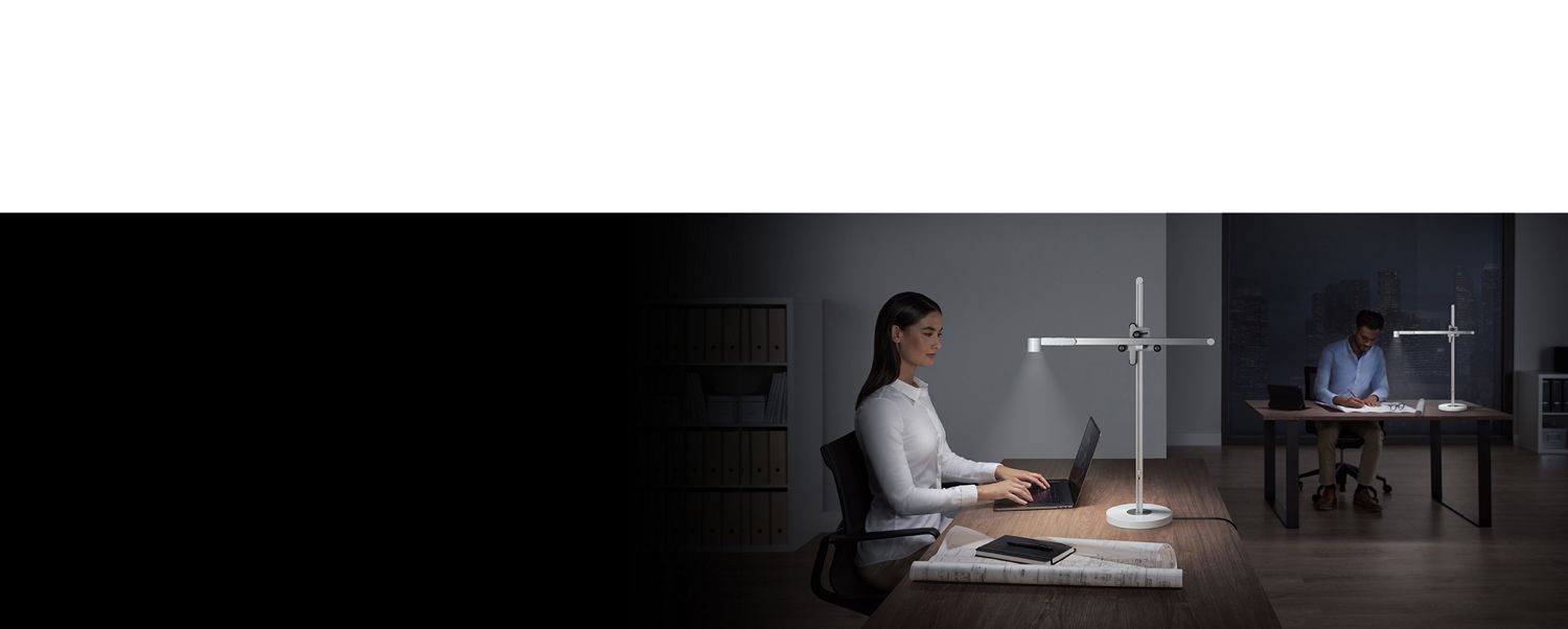 Mujer usando la lámpara Dyson Lightcycle para iluminar su espacio de trabajo. 