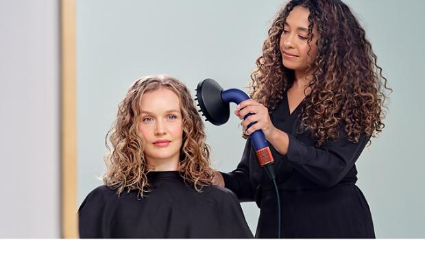 Bir modelin saçını Dyson Supersonic r saç kurutma makinesi ve Difüzör ile kurutan Dyson Global Stil Elçisi.