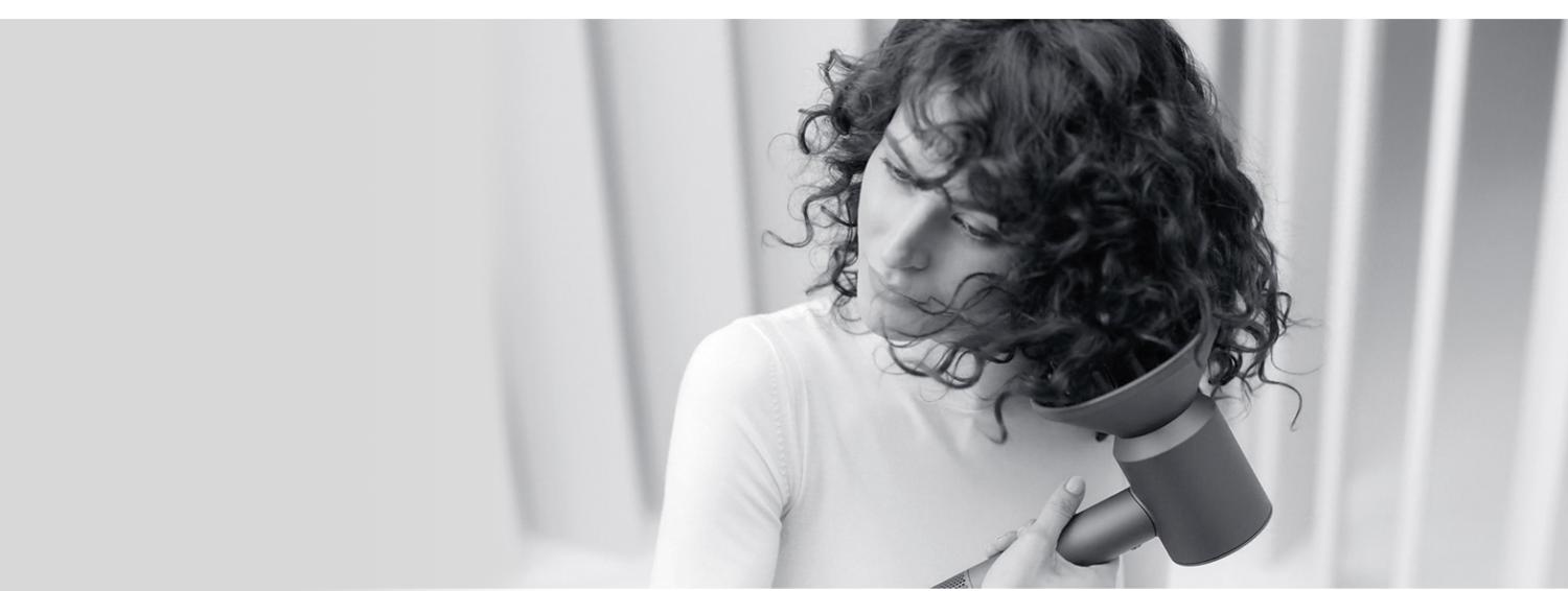 Femme se séchant les cheveux avec le sèche-cheveux Dyson Supersonic équipé d'un diffuseur.