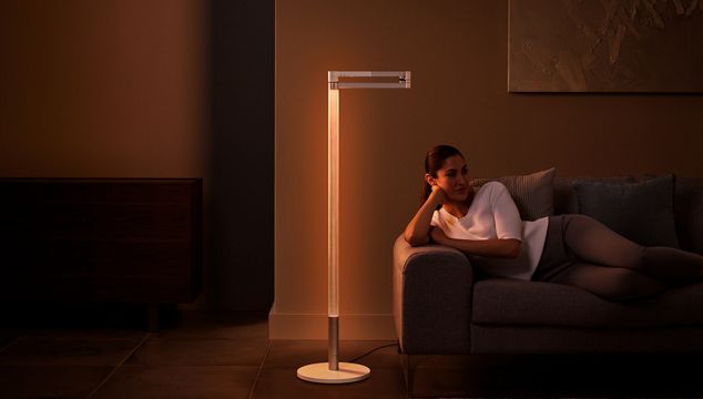 Woman relaxing under Dyson Solarcycle Morph ambient light in a hotel atrium.