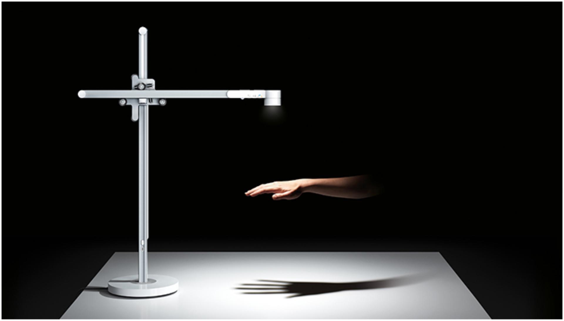 وحدة الإضاءة المكتبية Dyson Lightcycle تُشِع ضوءاً فوق يد في غرفة مُظلمة