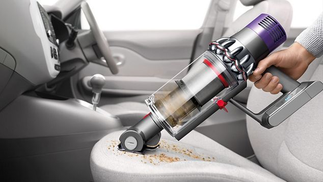 Le Dyson Cyclone V10 utilisé en tant qu'aspirateur à main pour le nettoyage de l'habitacle d'une voiture