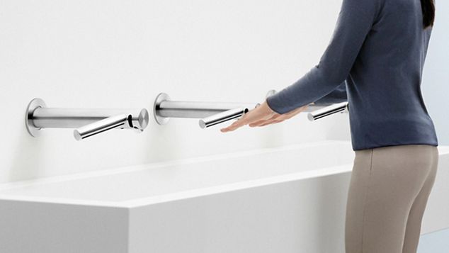 公衆トイレでDyson Wash+Dryハンドドライヤーで手を乾かす人