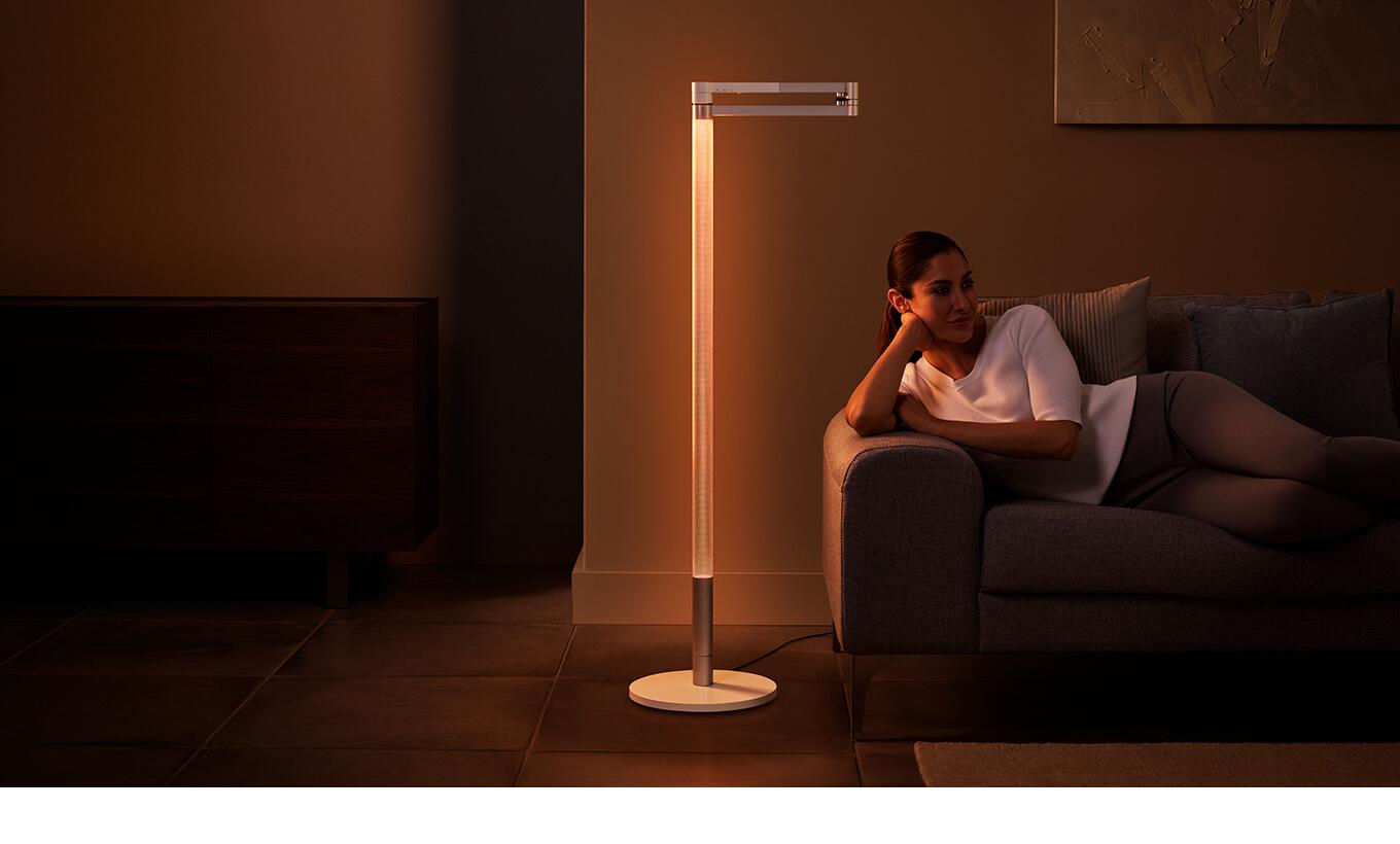 A woman relaxing under the Dyson Solarcycle Morph standing lamp