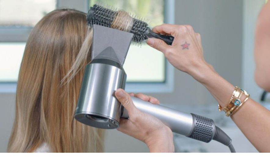 Professional hair stylist using the Dyson Supersonic hair dryer on a customer
