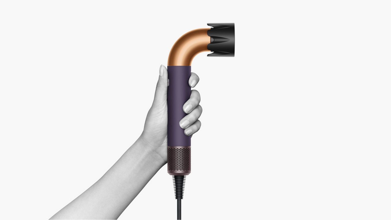 A hand holding the Dyson Supersonic r Professional hair dryer in Bright copper.