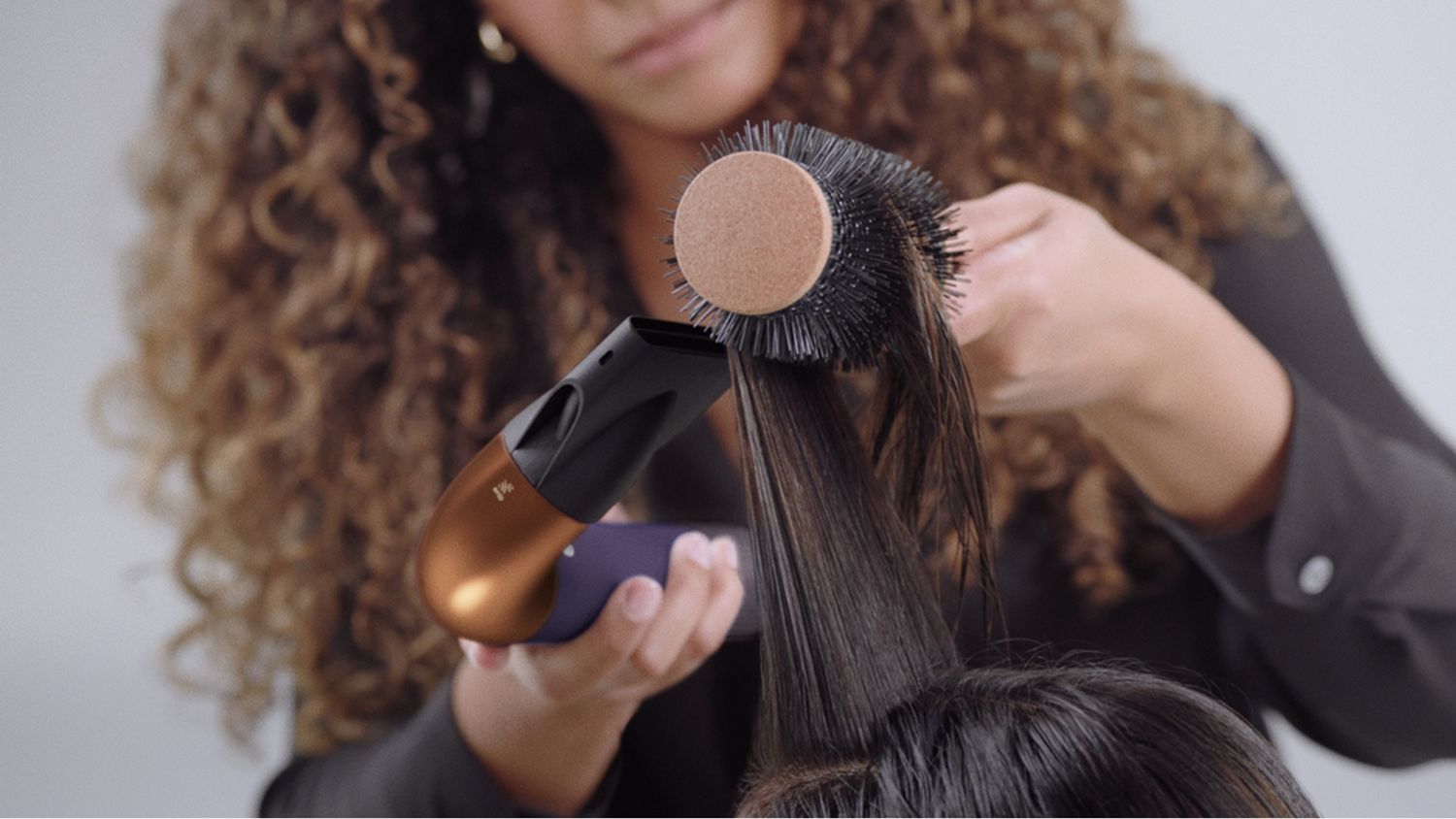 A stylist using the Dyson Supersonic r Professional hair dryer in Bright copper.