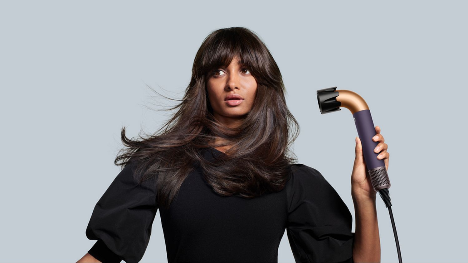 A model using the Dyson Supersonic r Professional hair dryer in Bright copper.