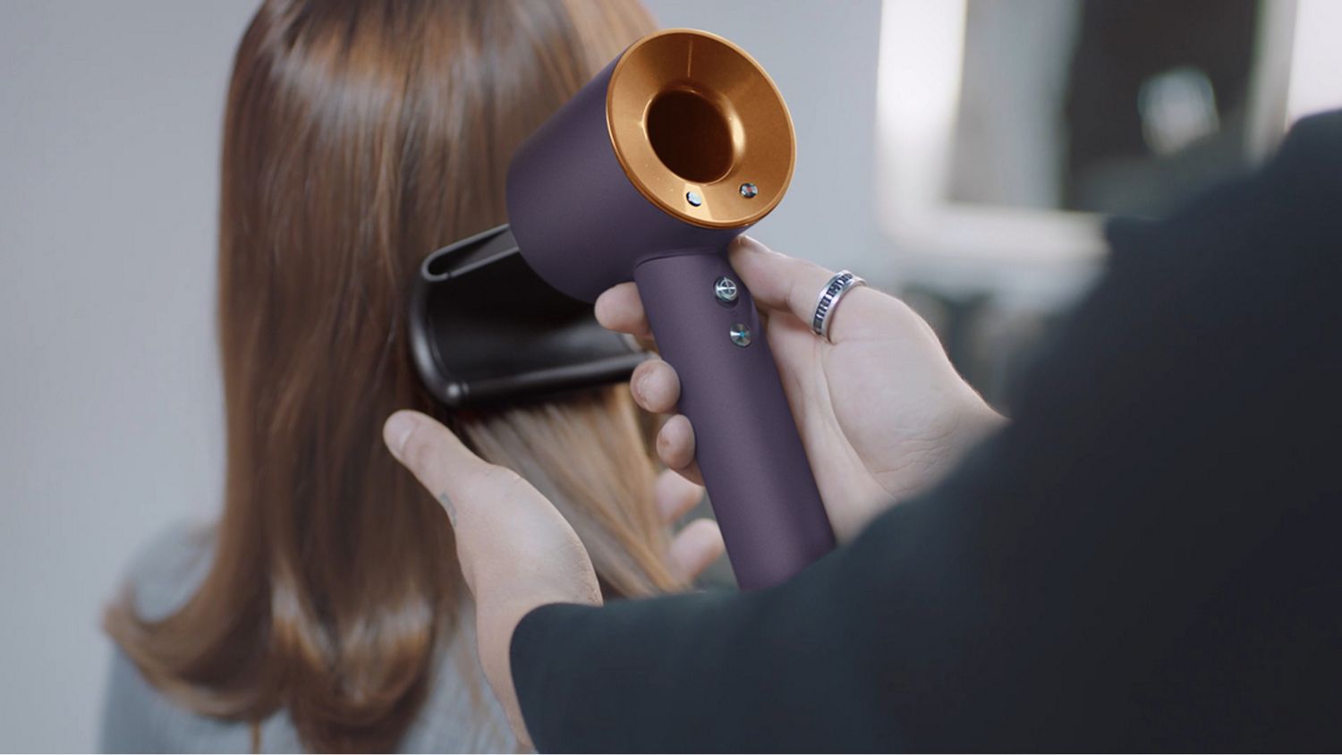 A stylist using the Dyson Supersonic r Professional hair dryer in Bright copper with the Flyaway attachment.