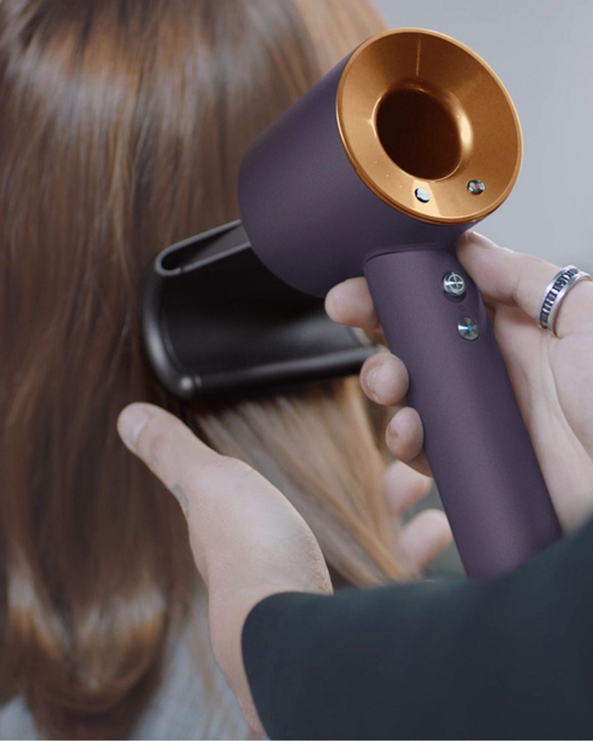 A stylist using the Dyson Supersonic r Professional hair dryer in Bright copper with the Flyaway attachment.