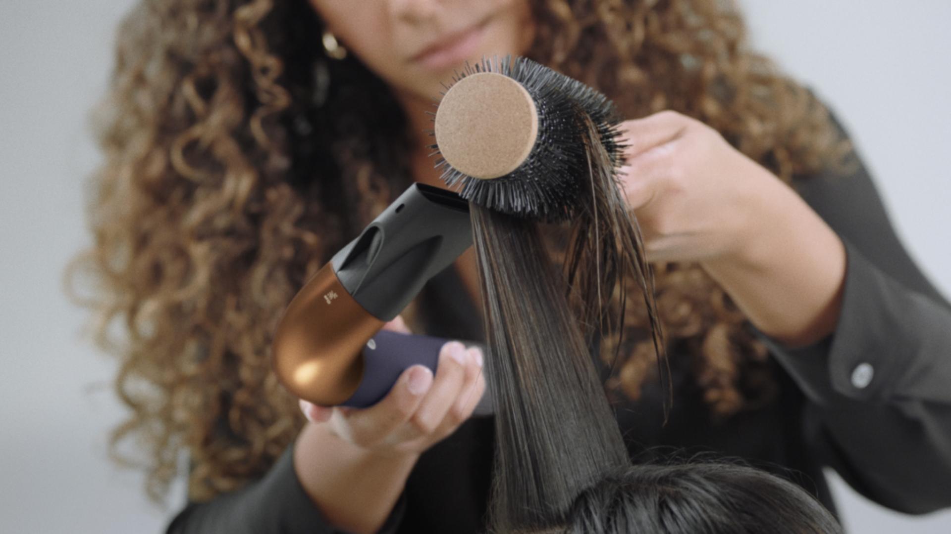 A stylist using the Dyson Supersonic r Professional hair dryer in Bright copper.