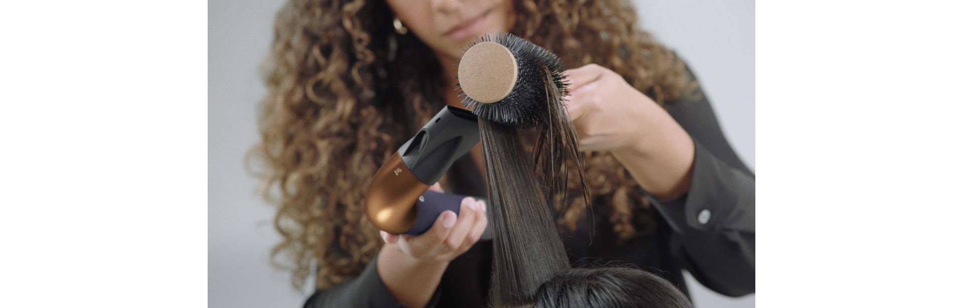 A stylist using the Dyson Supersonic r Professional hair dryer in Bright copper.